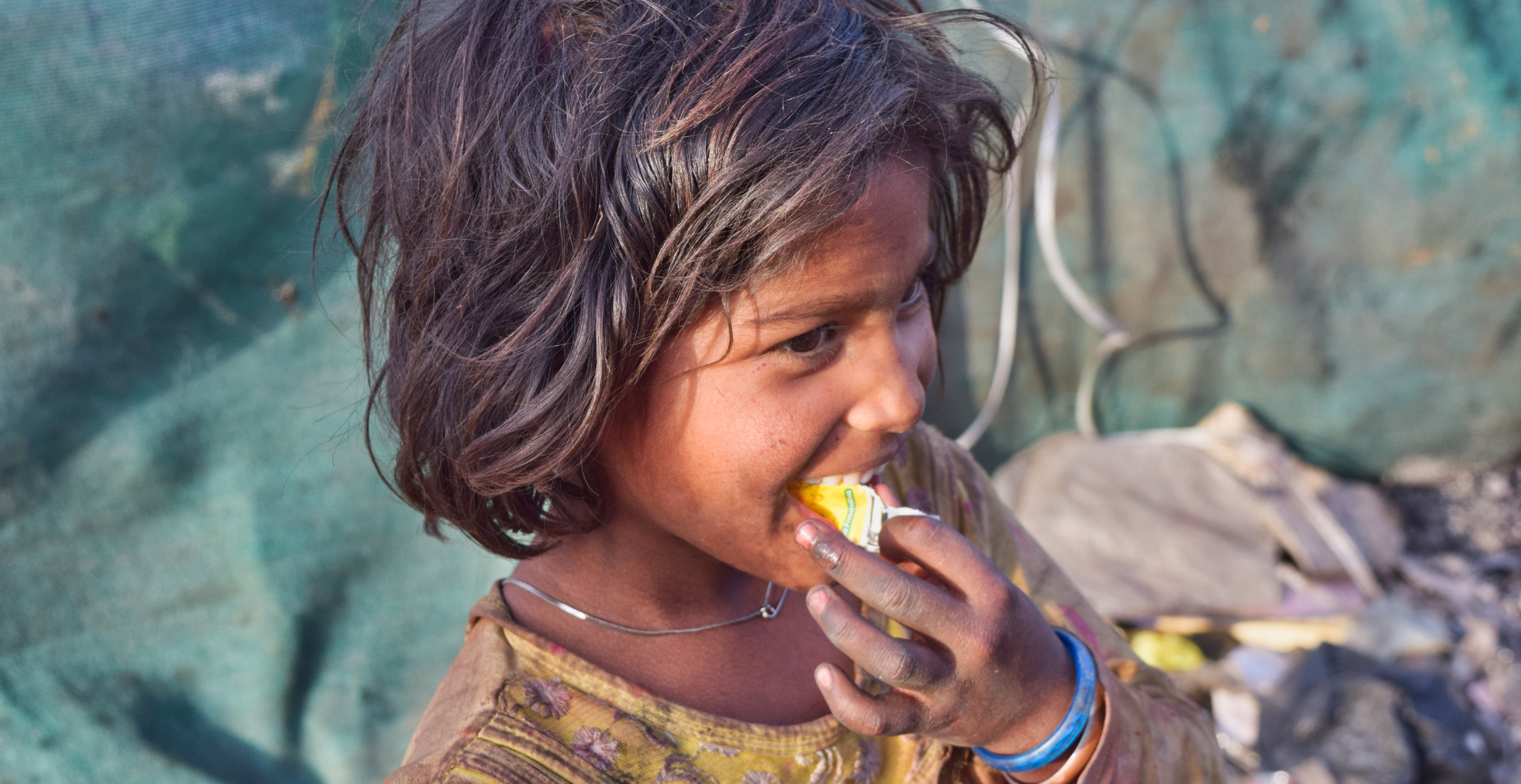 A young girl is eating a piece of food from her hand.