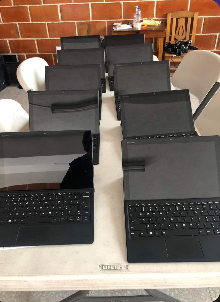 A row of black laptops are sitting on a white table.