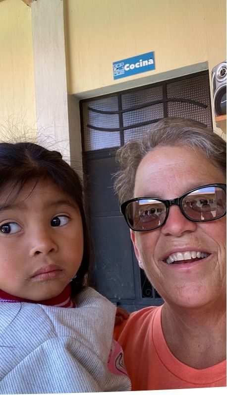 A woman wearing sunglasses is holding a little girl in her arms.