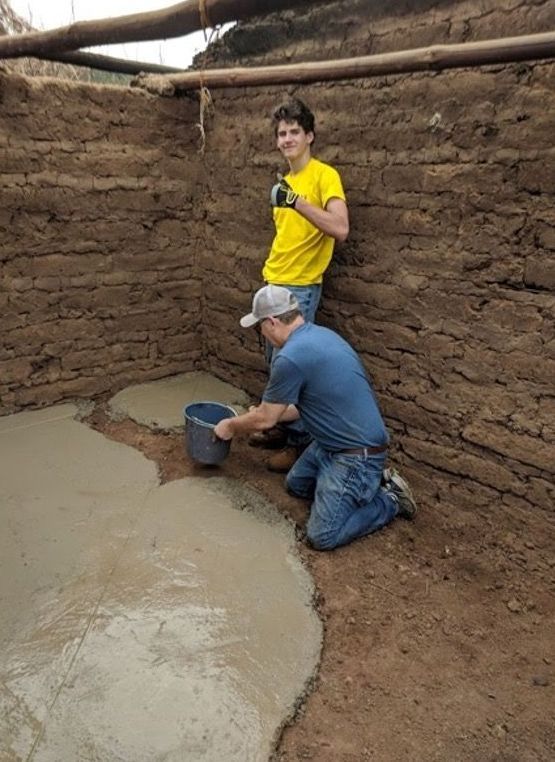 Two men are working on a concrete floor in a room