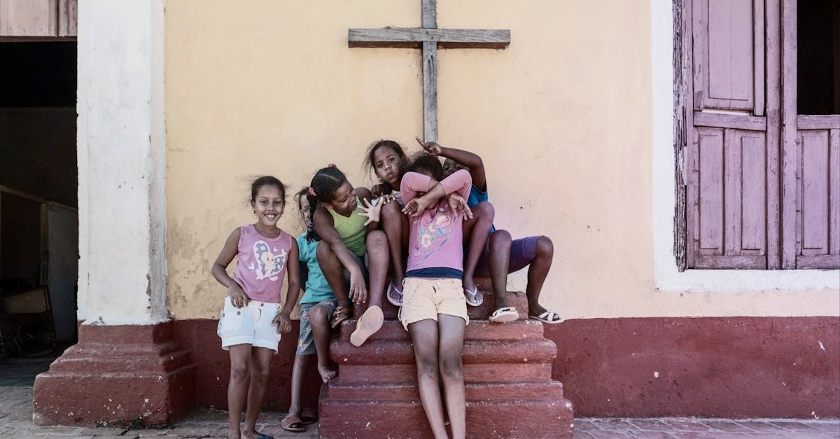 A group of children are posing for a picture in front of a cross.