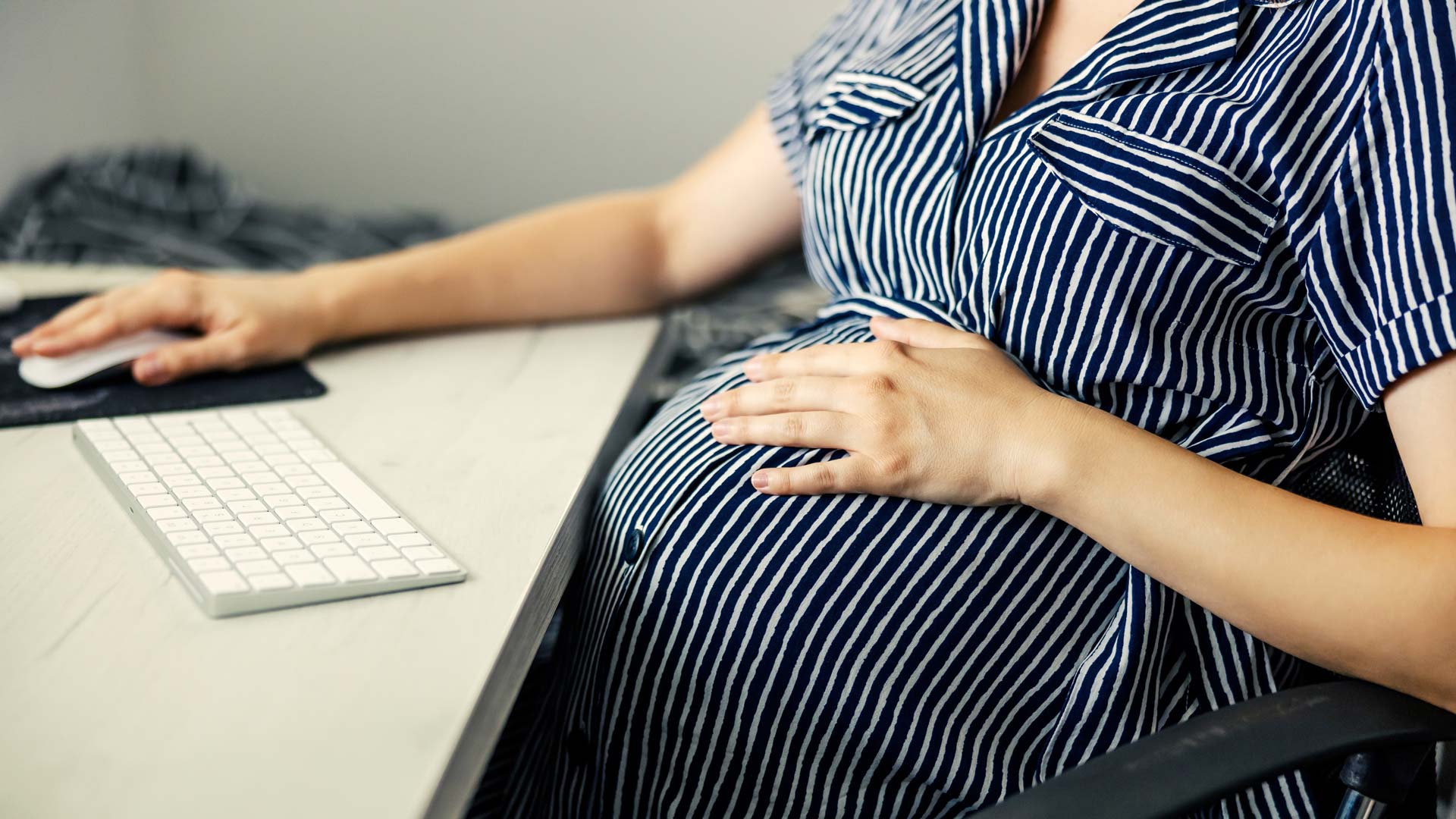 Schwangere Frau am Schreibtisch informiert sich über Mutterschutz