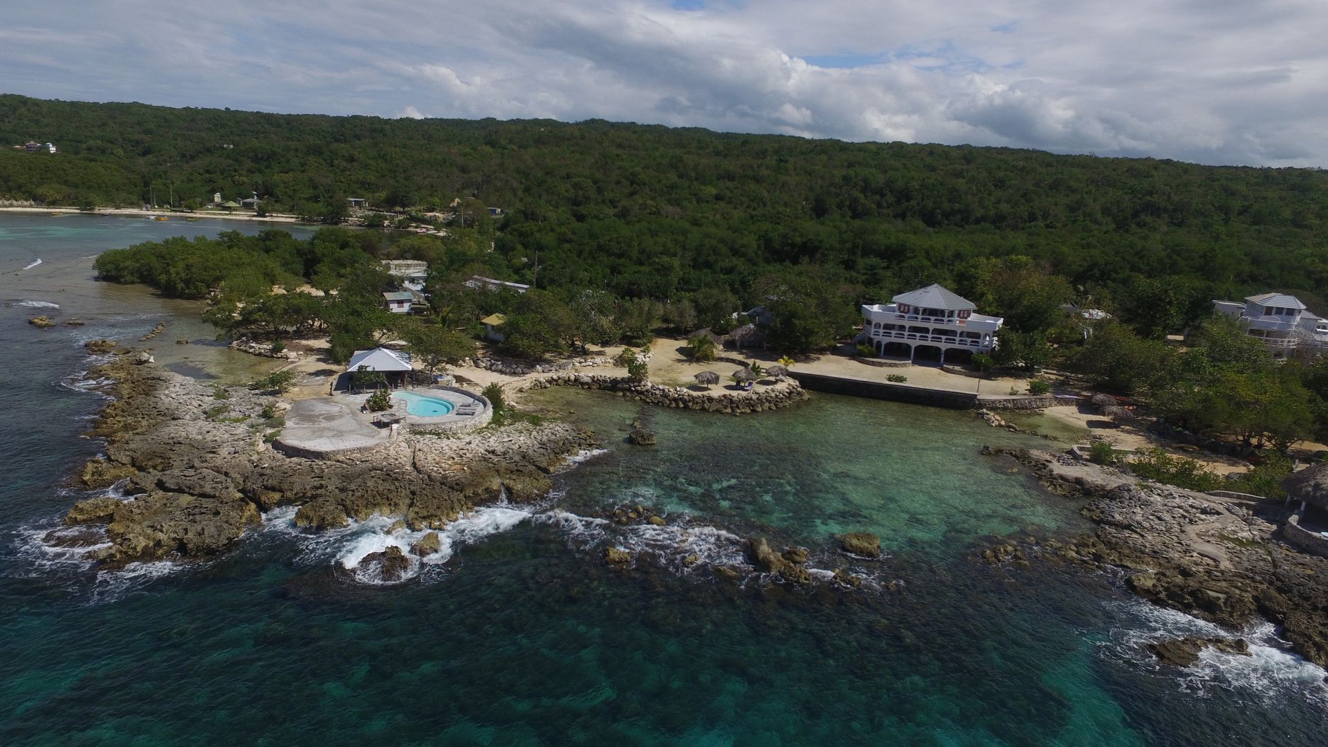 An aerial view of a small island in the middle of the ocean surrounded by trees.