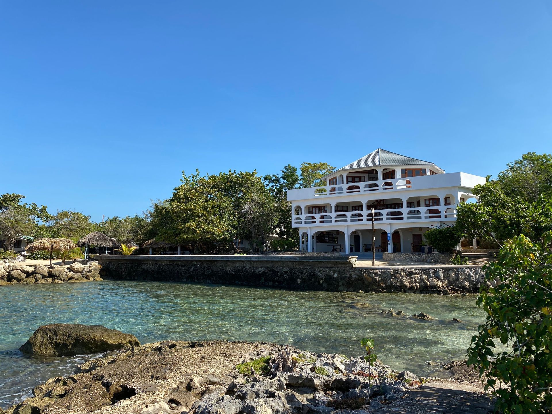 A large white house sits on the shore of a body of water