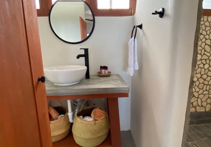 A bathroom with a sink , mirror and baskets.