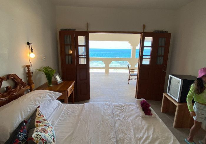 A woman in a pink hat is standing in a bedroom with a view of the ocean.