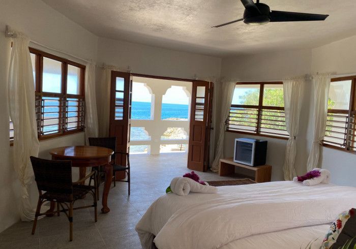 A bedroom with a ceiling fan and a view of the ocean