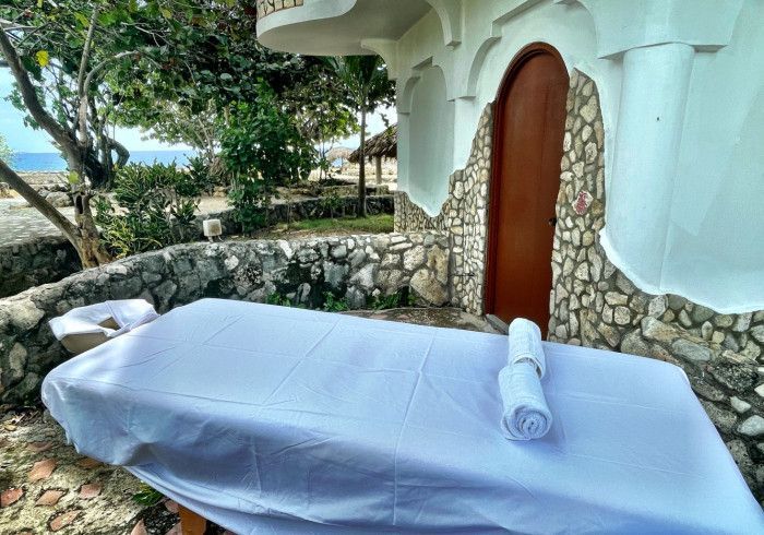 A massage table with two towels on it in front of a stone wall.