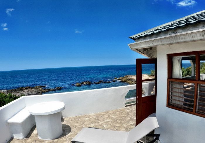 A balcony overlooking the ocean with a table and chairs