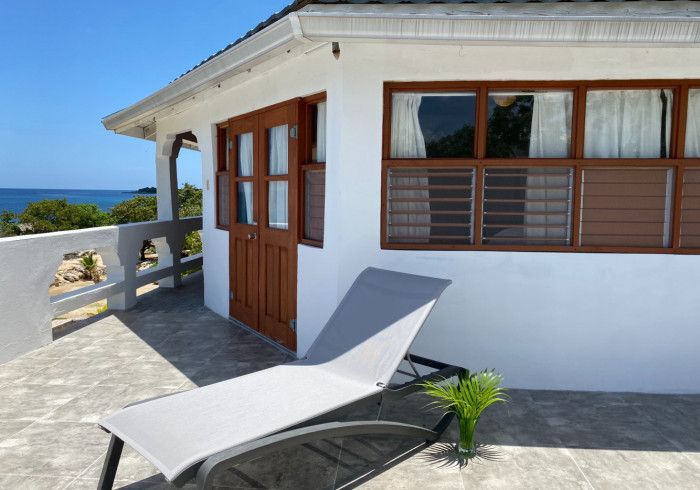 A white house with a lounge chair in front of it