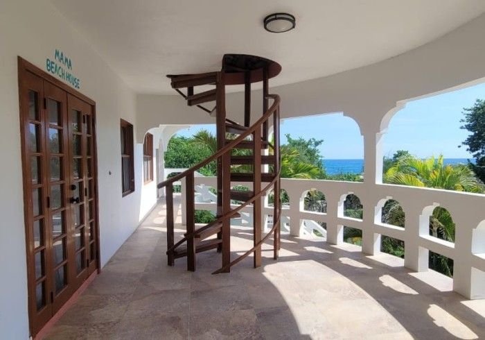 A spiral staircase leading up to a balcony overlooking the ocean