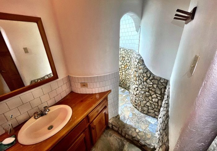 A bathroom with a sink , mirror and shower.