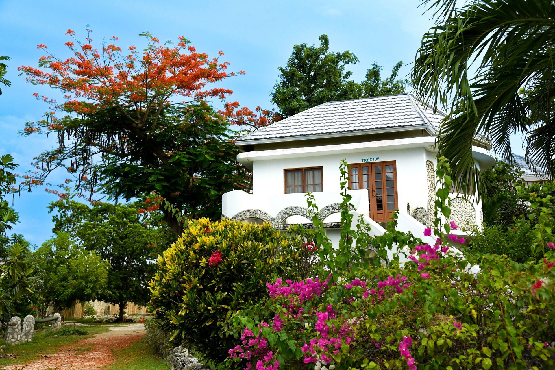 A white house is surrounded by flowers and trees