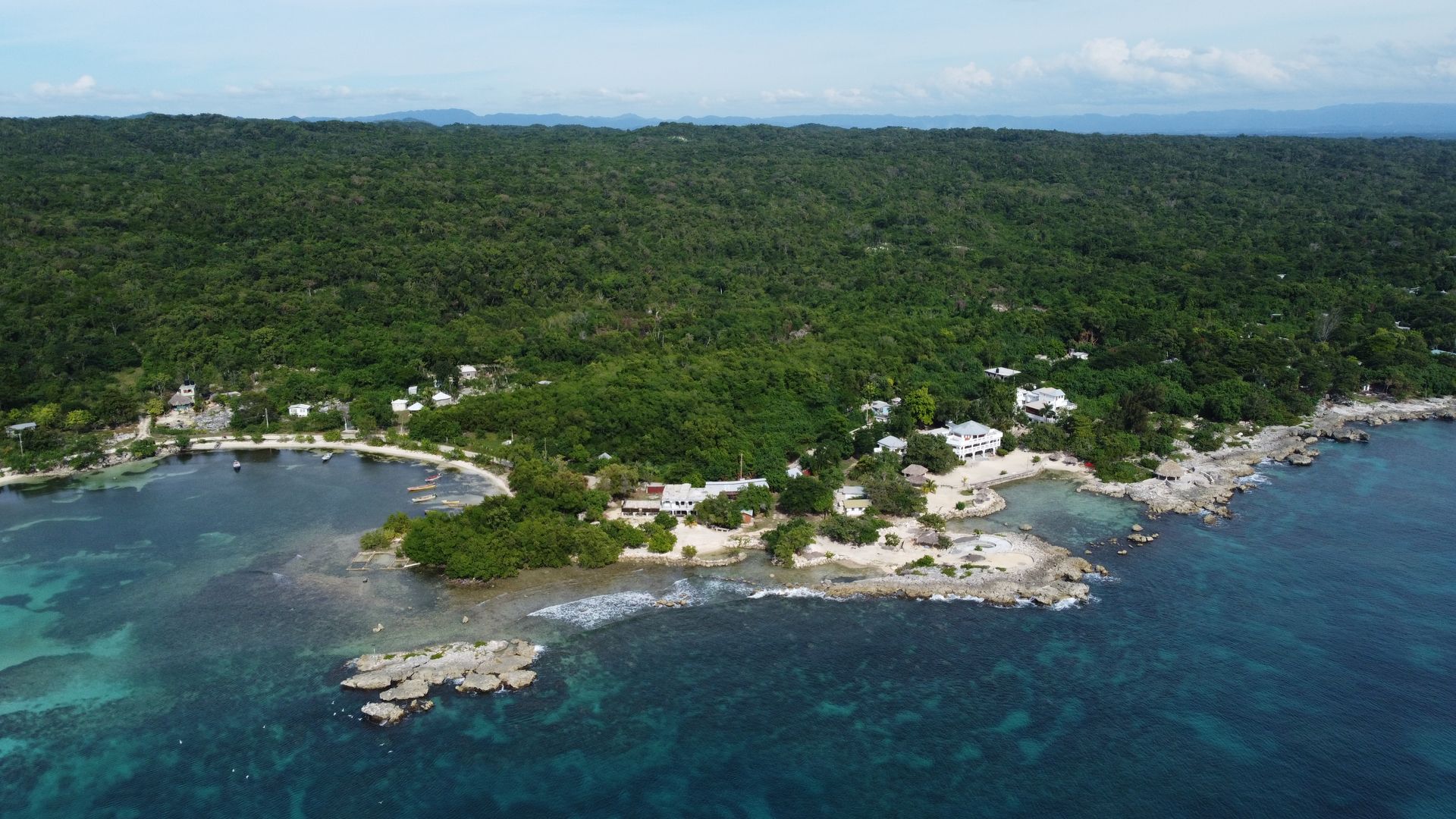 An aerial view of a small island in the middle of the ocean surrounded by trees.