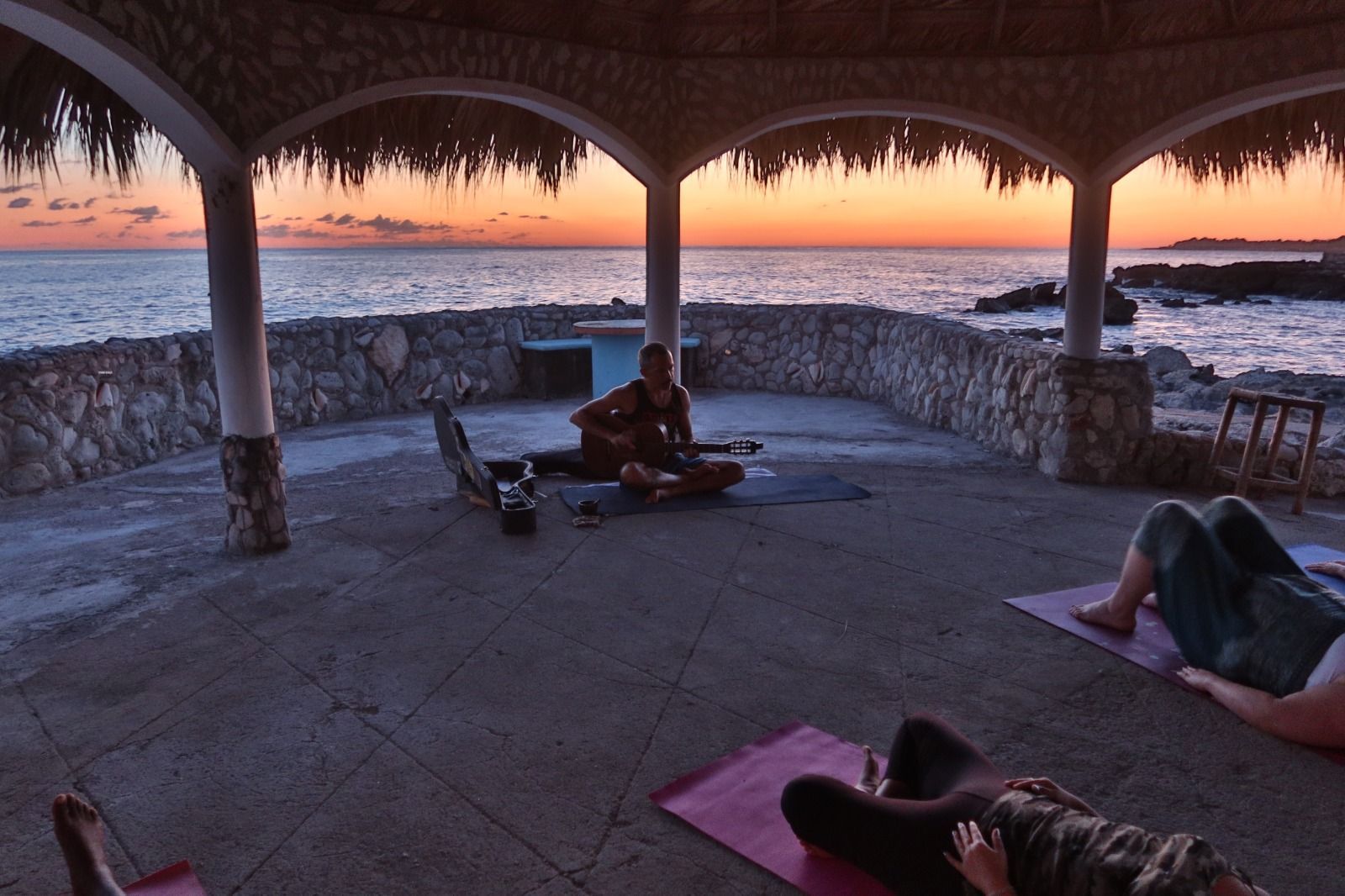 A man is playing a guitar in a gazebo overlooking the ocean