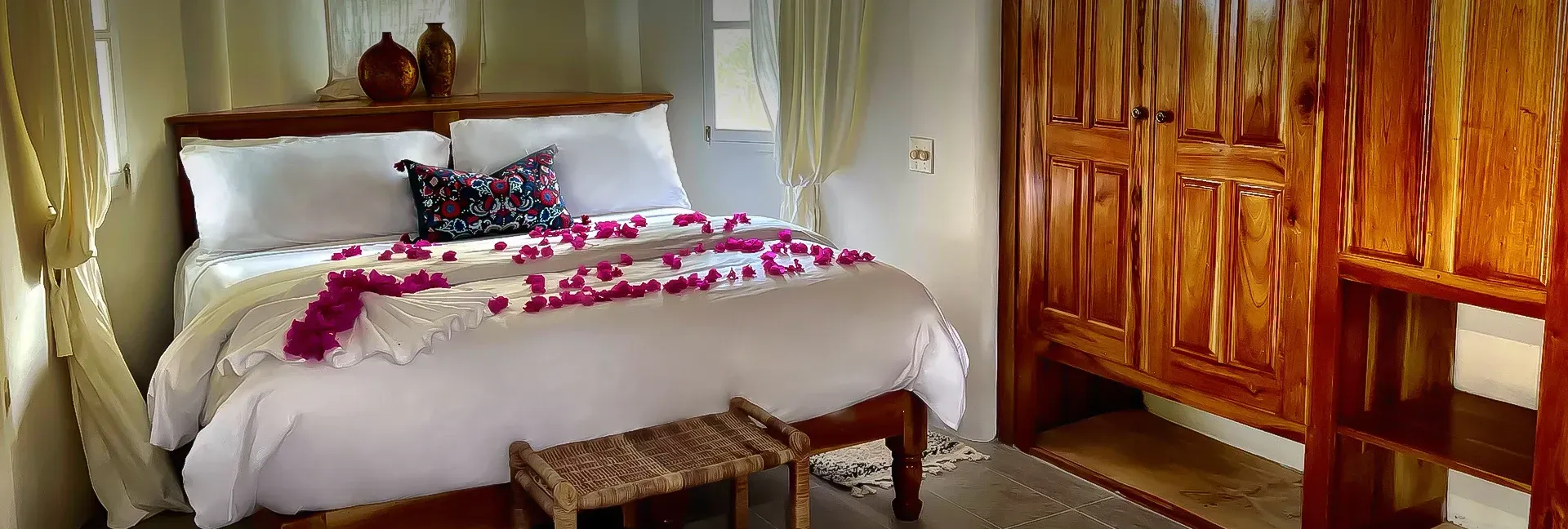 A bedroom with a bed , a bench , and a wardrobe.