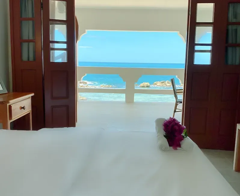 A bedroom with a balcony overlooking the ocean