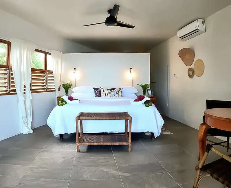 A bedroom with a king size bed and a ceiling fan.