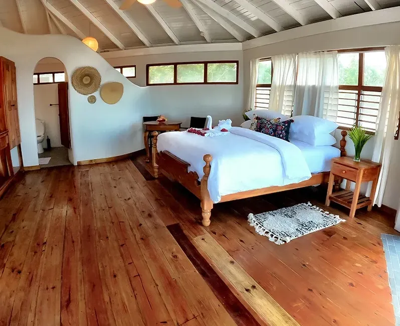 A bedroom with a large bed and wooden floors