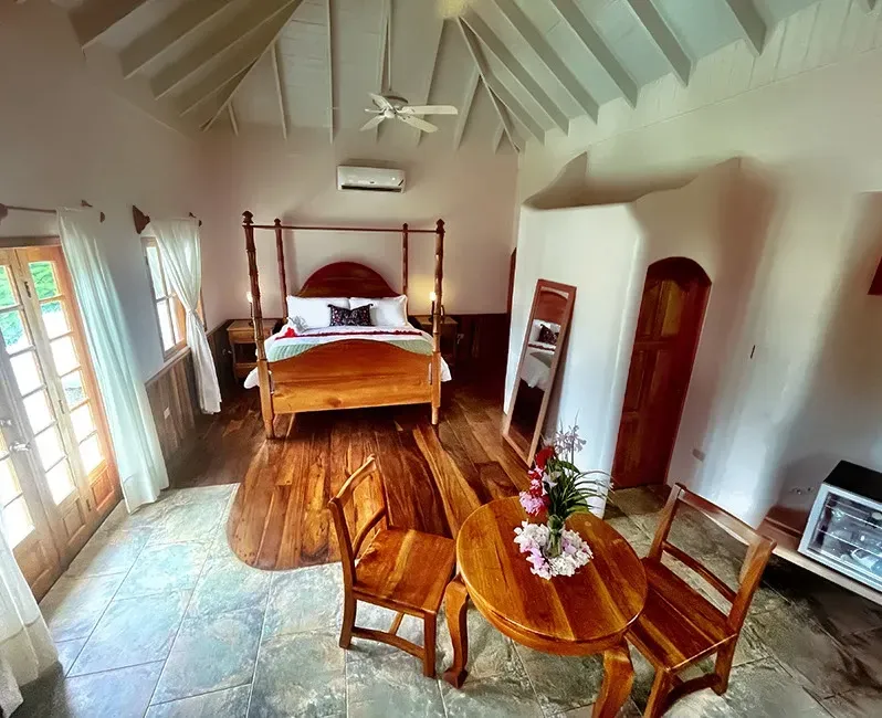 A bedroom with a four poster bed , a table and chairs.