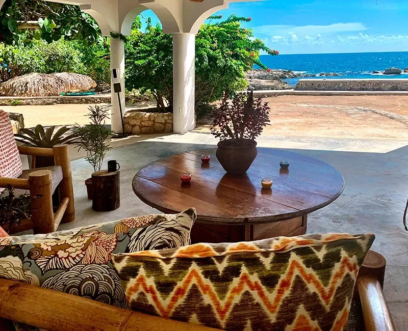 A living room with a table and chairs and a view of the ocean