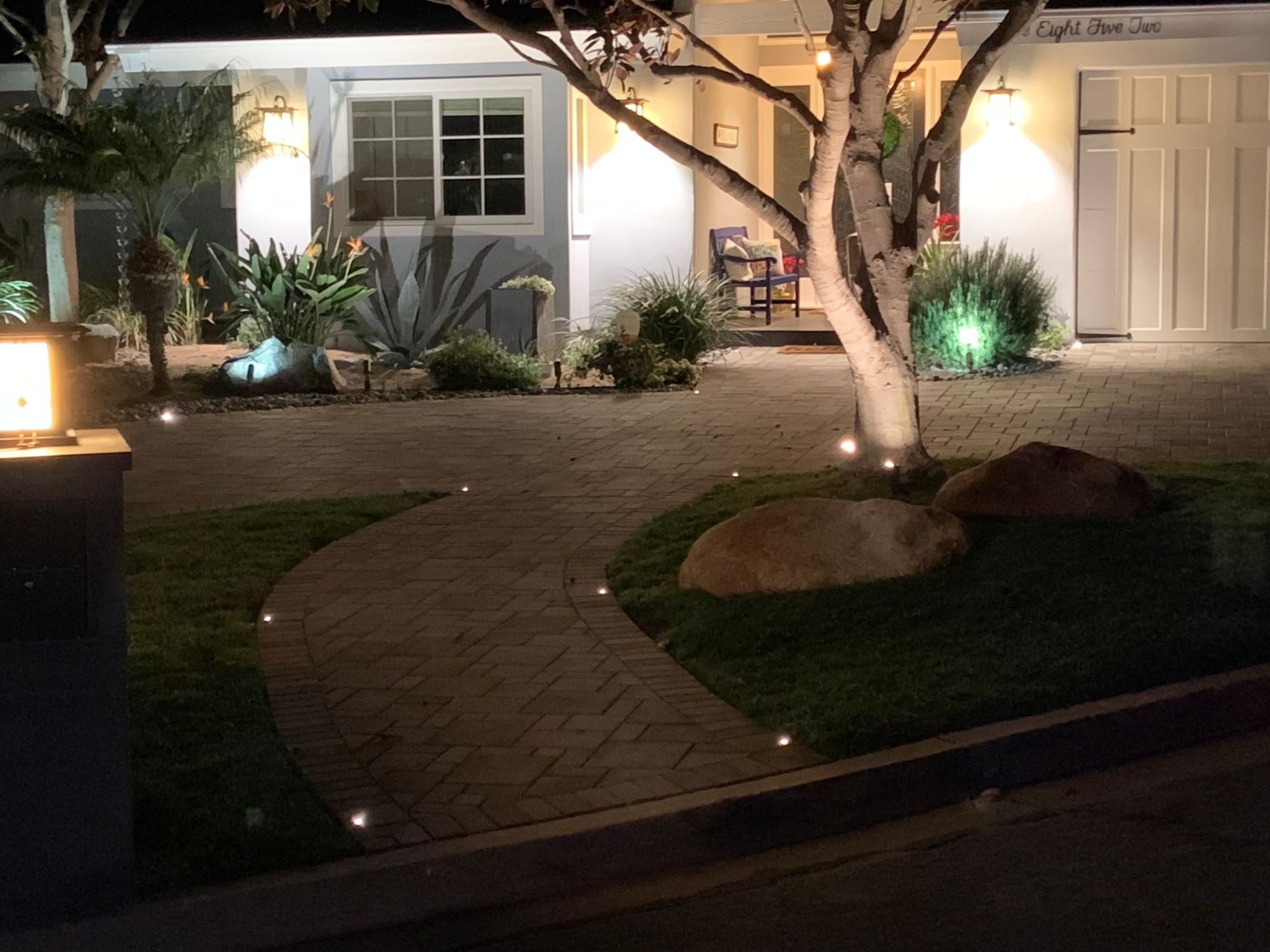 A lit front walkway leads to a house at night.