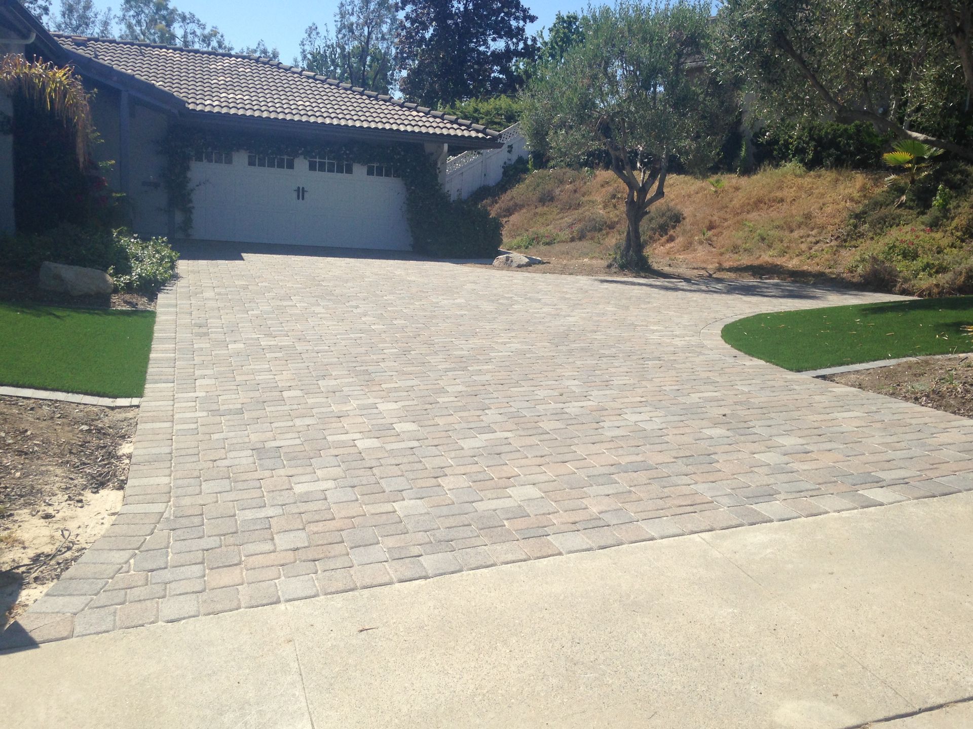 A multi-colored paver driveway leads to a suburban home garage.