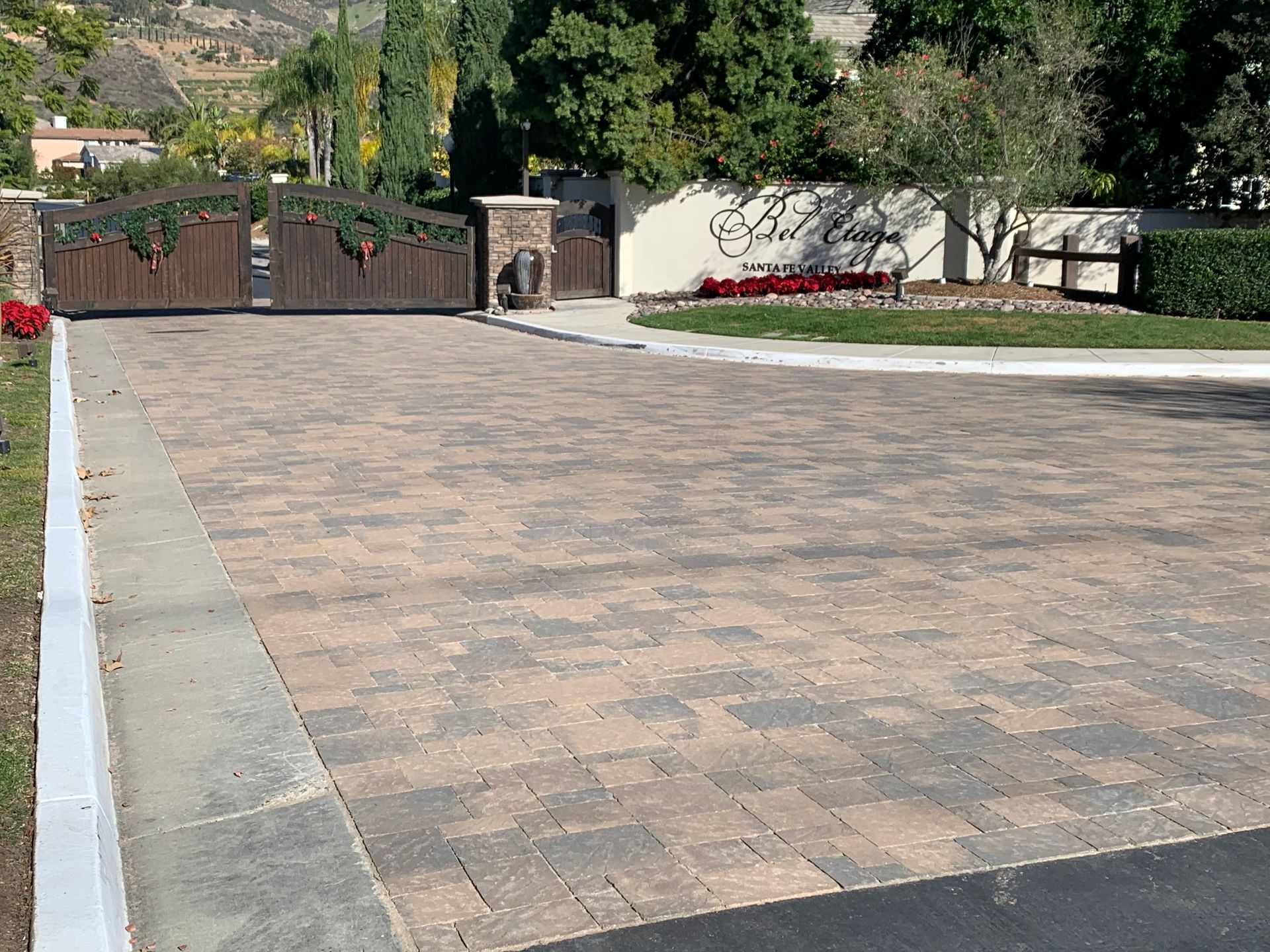 A wide paved driveway leads to an arched metal gate entrance.