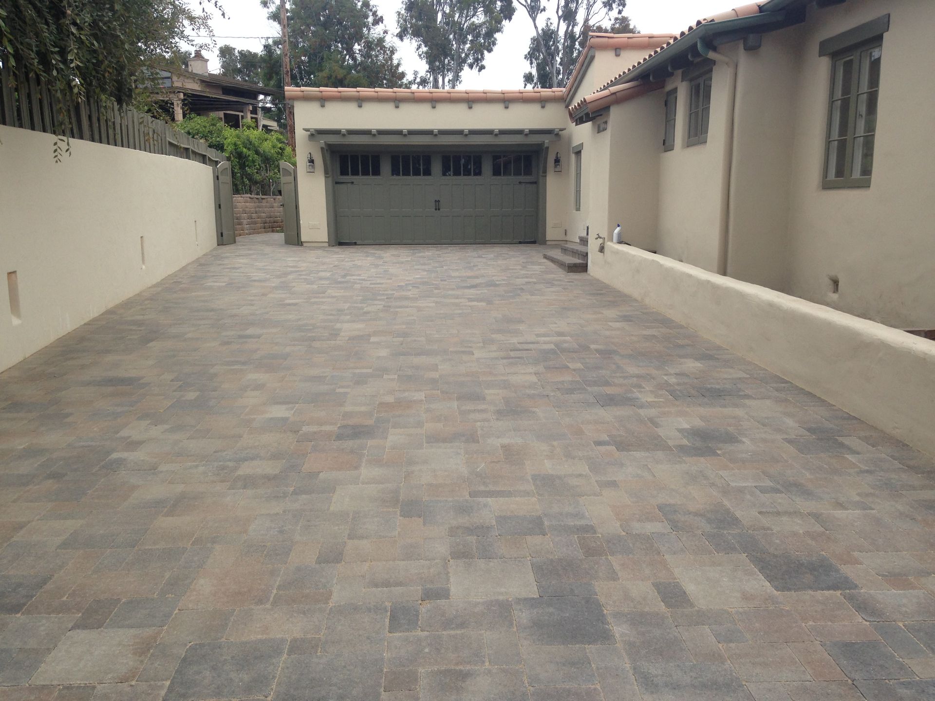 A wide, paved driveway leading to a garage between two low stucco walls.