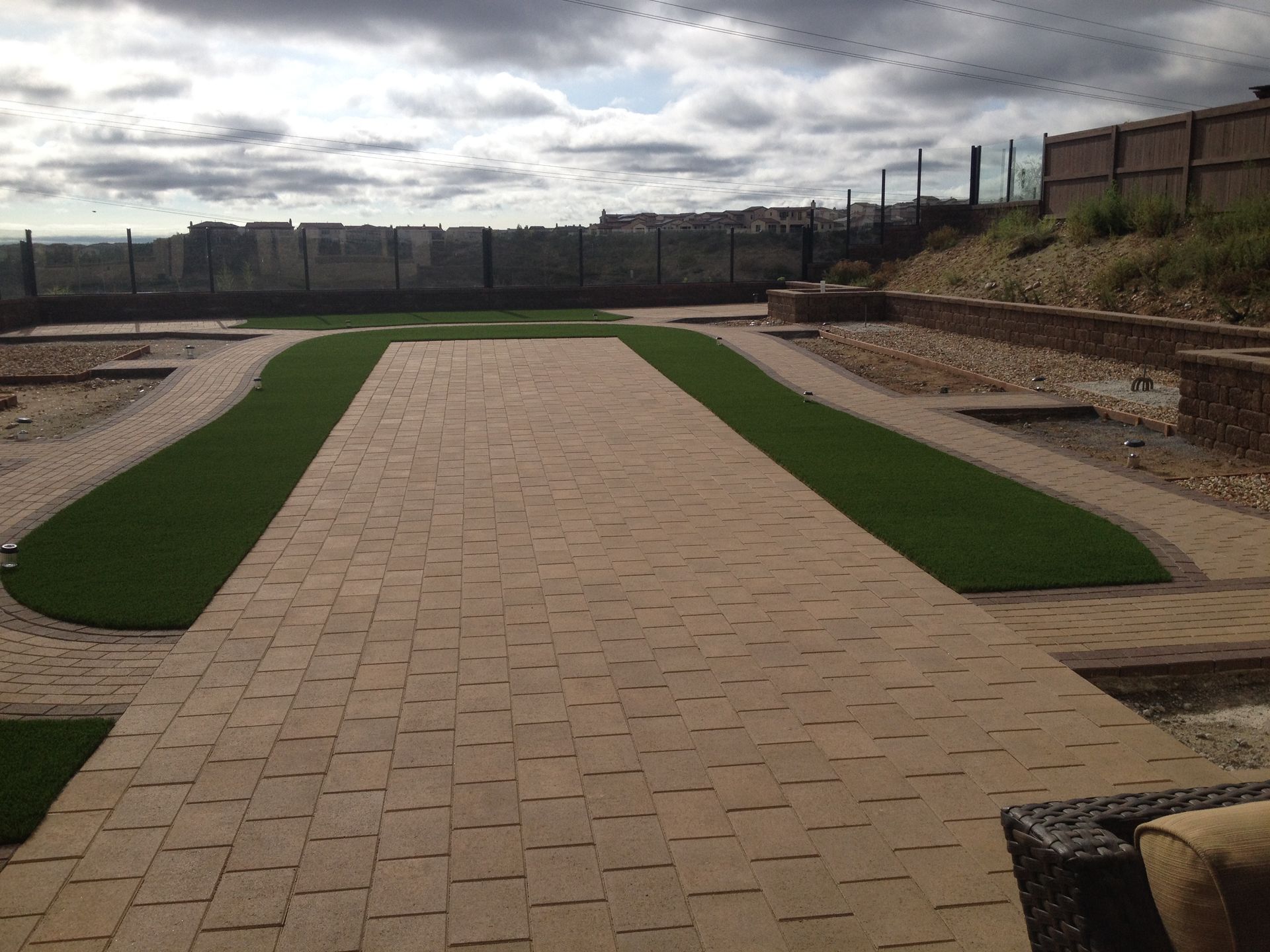 A backyard patio featuring a central rectangular paver walkway.