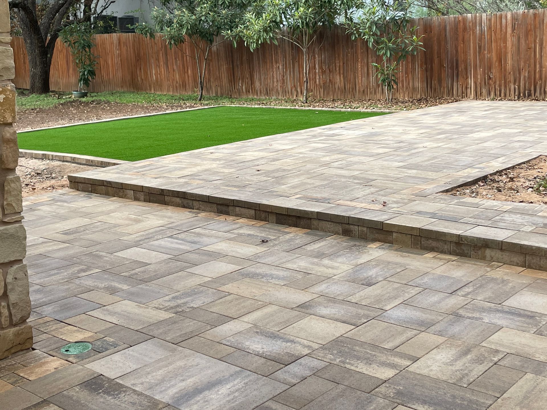A tiered backyard patio with grey paverrs.