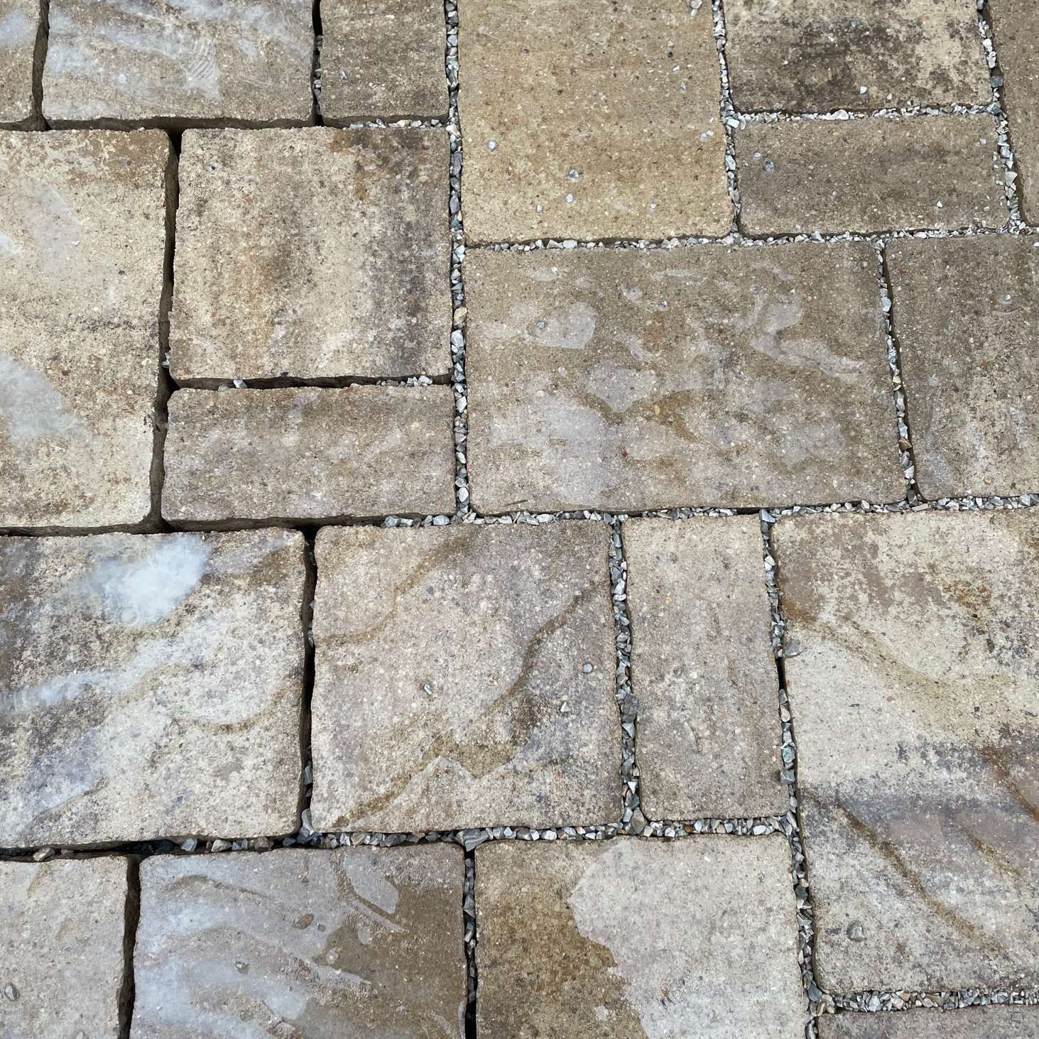 A top-down view of stone patio pavers in varying rectangular sizes with beige and gray tones.