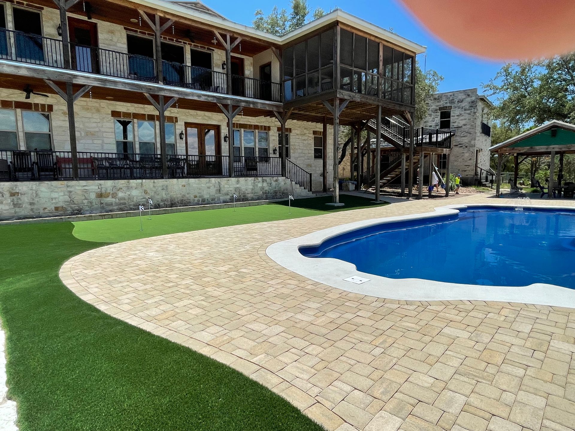 A two-story stone house with a balcony and screen porch.
