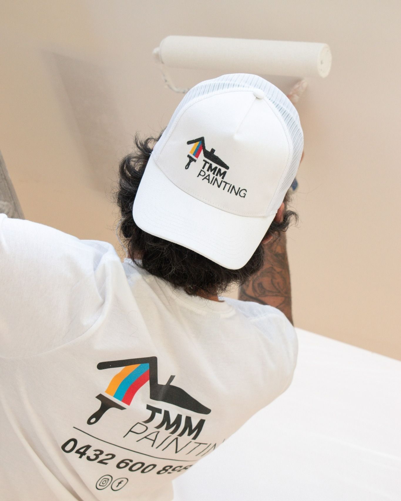 A Man Wearing a TMM Painting Hat is Painting a Wall — TMM Painting in Broadbeach, QLD