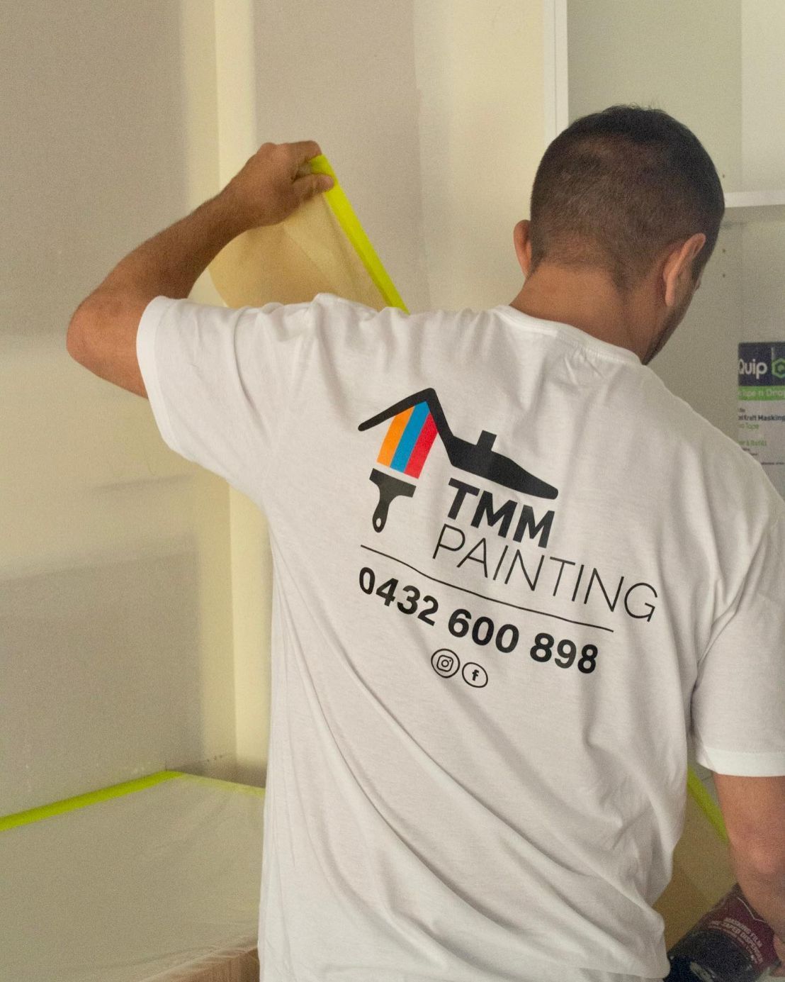 A Man Wearing a White Shirt That Says TMM Painting — TMM Painting in Coolangatta, QLD