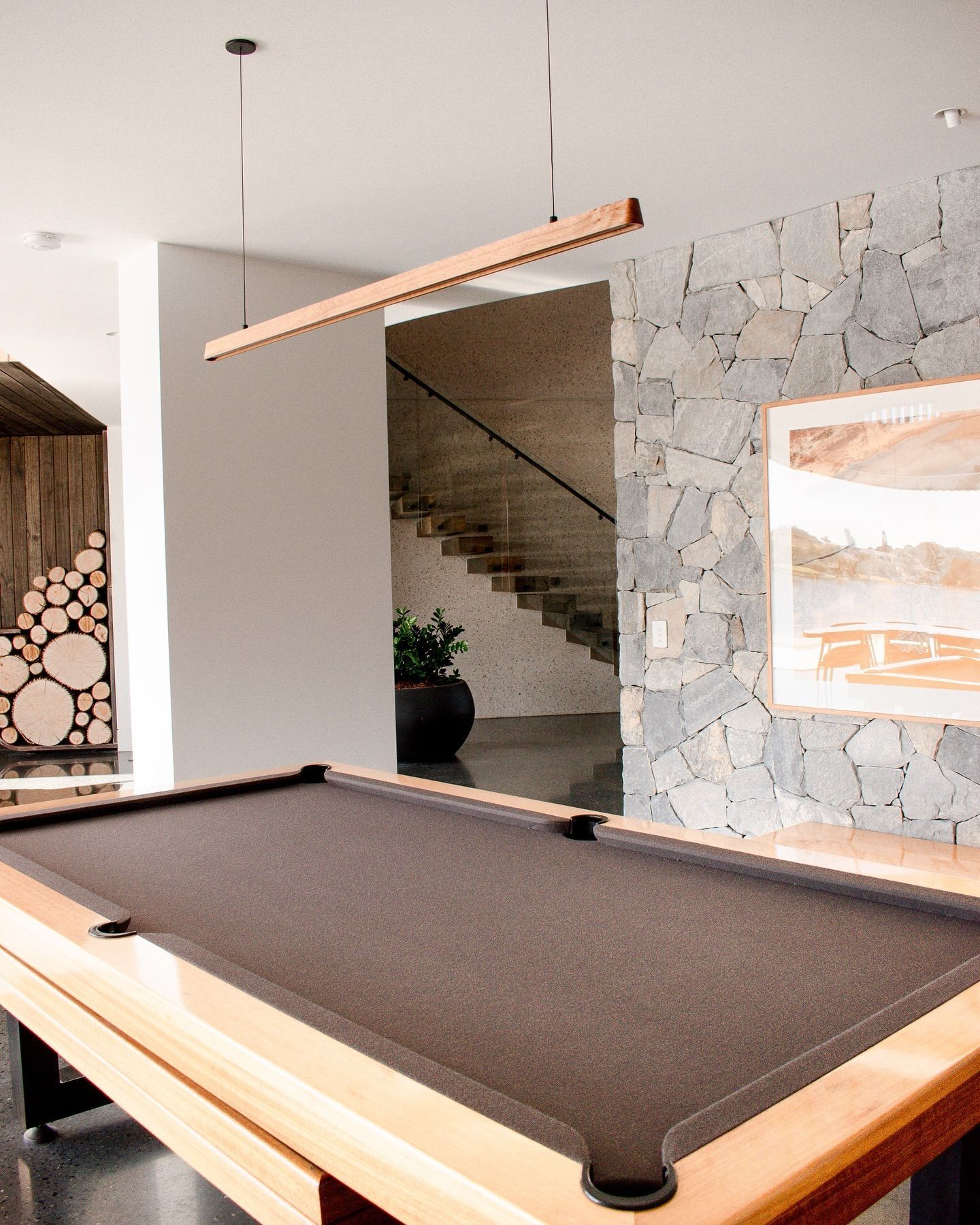 A pool table in a room with stairs in the background