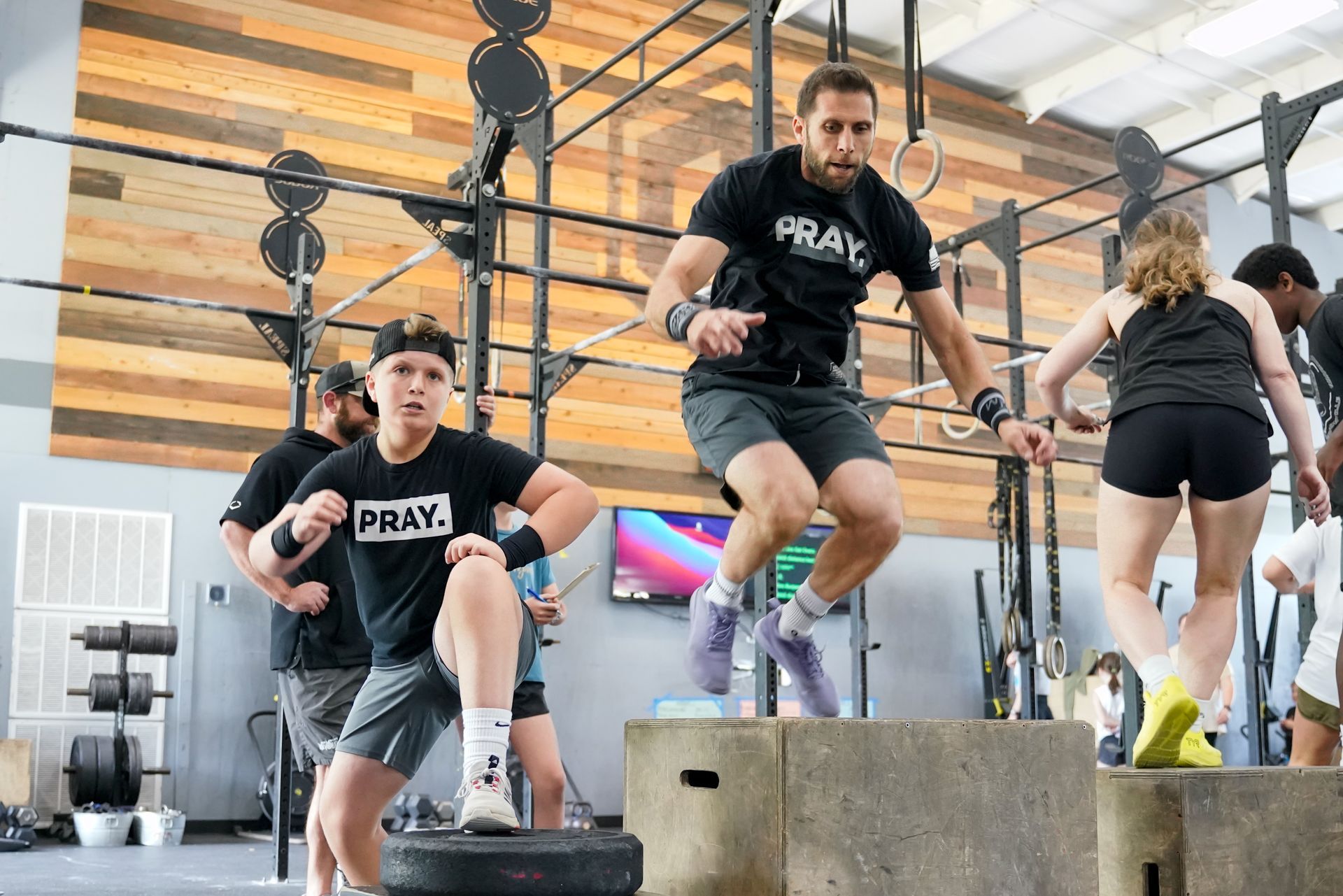 A group of people are jumping over boxes in a gym.