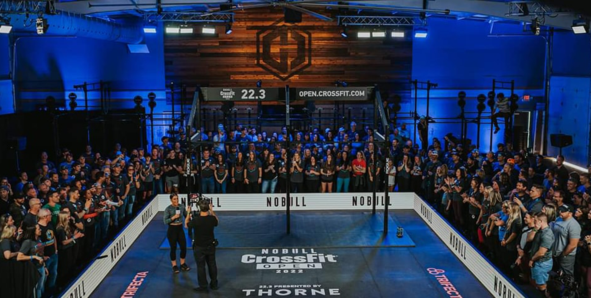 A large crowd of people are watching a boxing match in a gym.