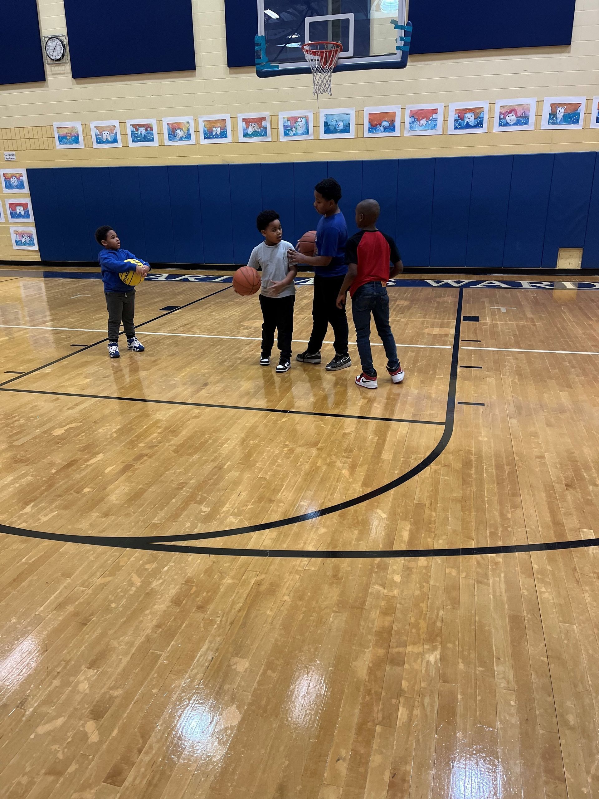 A group of children are playing basketball in a gym.