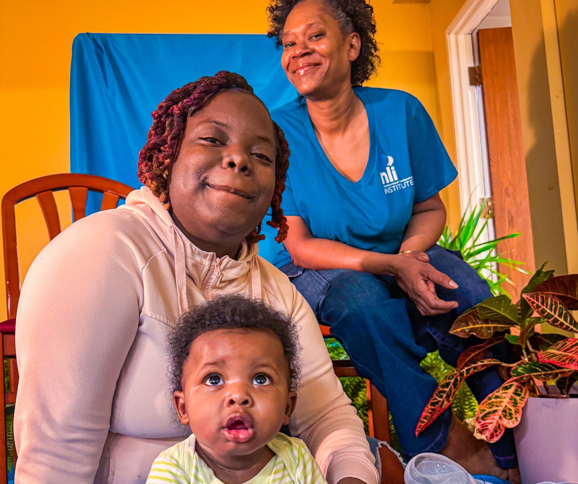 Two women are sitting next to a baby and smiling for the camera.