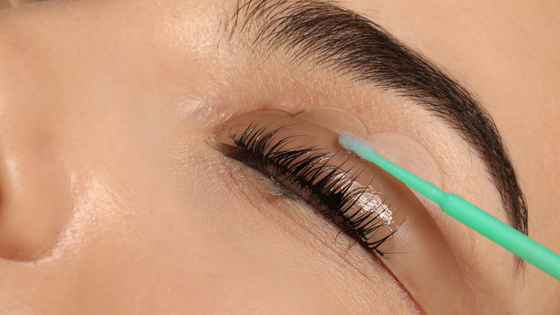 A woman is cleaning her eyelashes with a brush.
