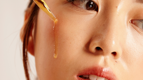 A close up of a woman applying a serum to her face.