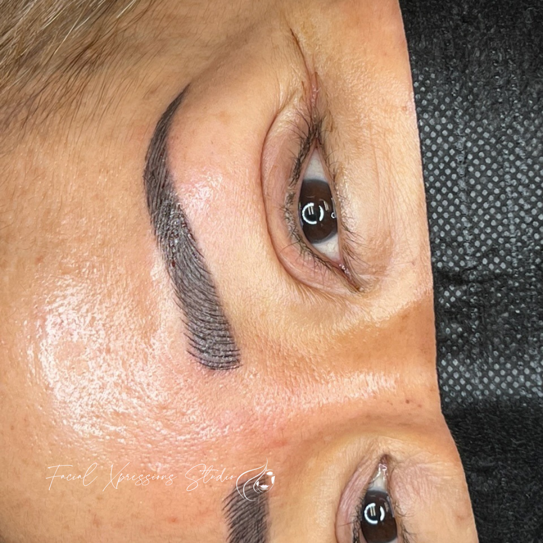 A close up of a woman 's face with a tattoo on her eyebrows.