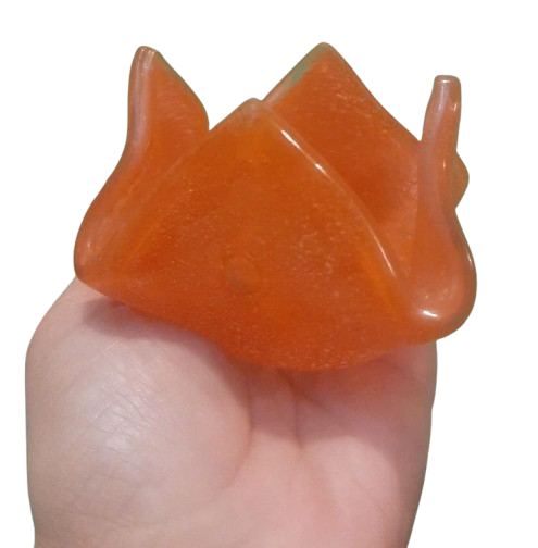 Una mano sostiene un objeto naranja en forma de flor.