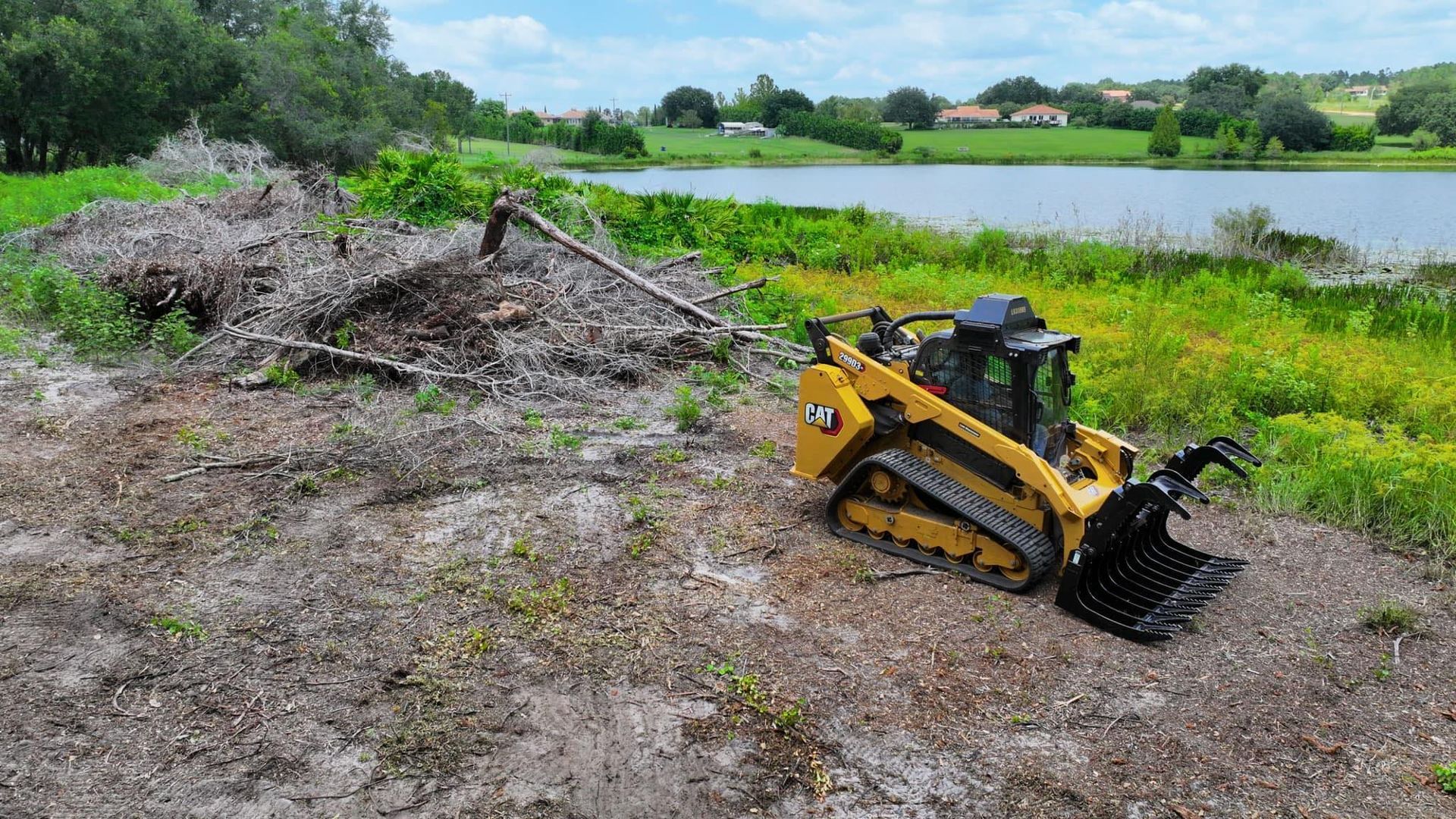 A bulldozer is sitting on top of a dirt field next to a lake.