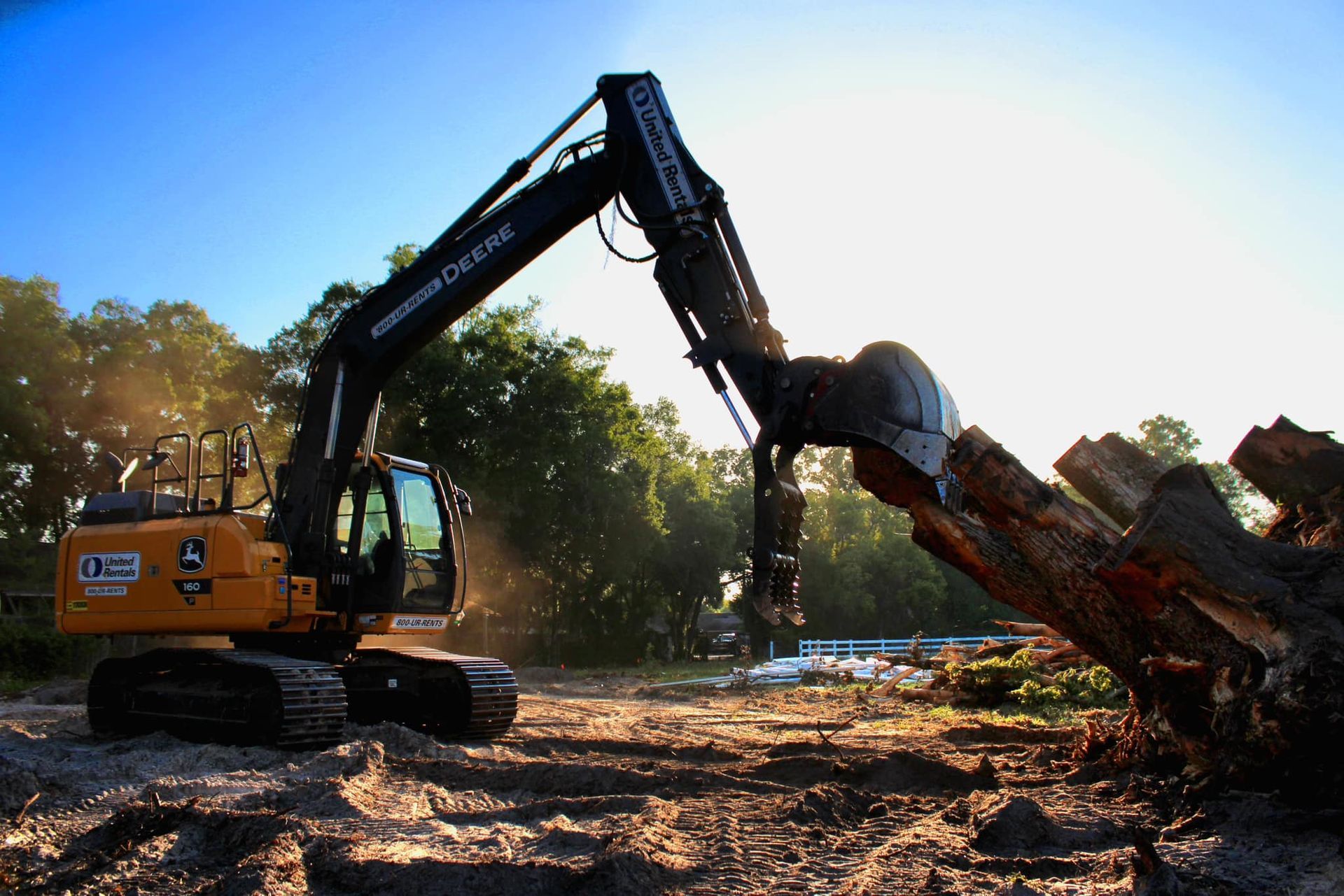 A large excavator is working on a pile of logs