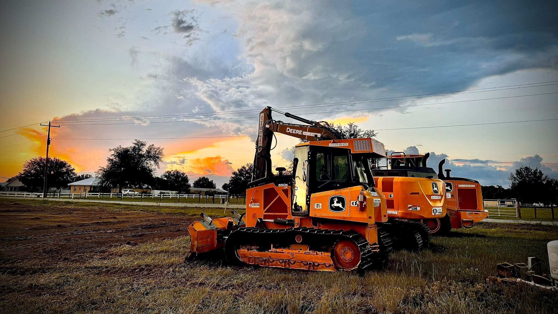 A bulldozer is parked in a field at sunset.