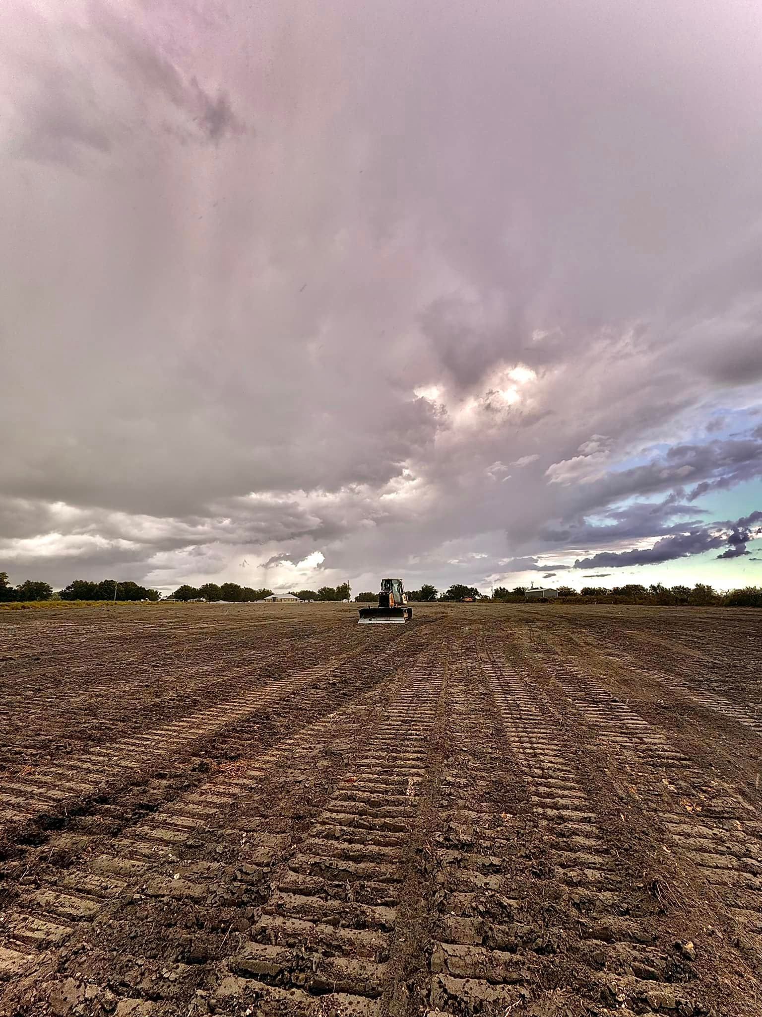 A tractor is plowing a field under a cloudy sky.