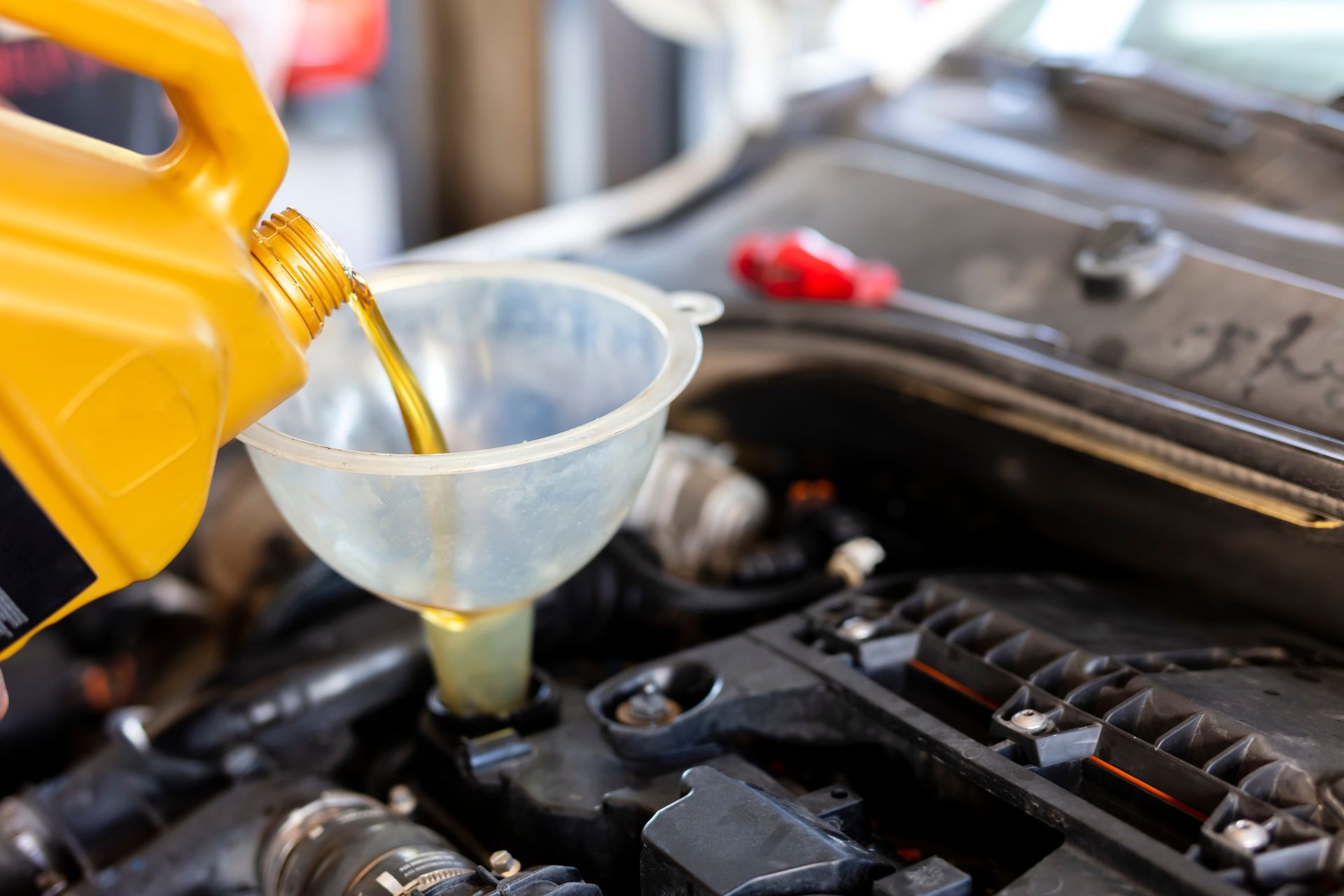A person is pouring oil into a car engine through a funnel.