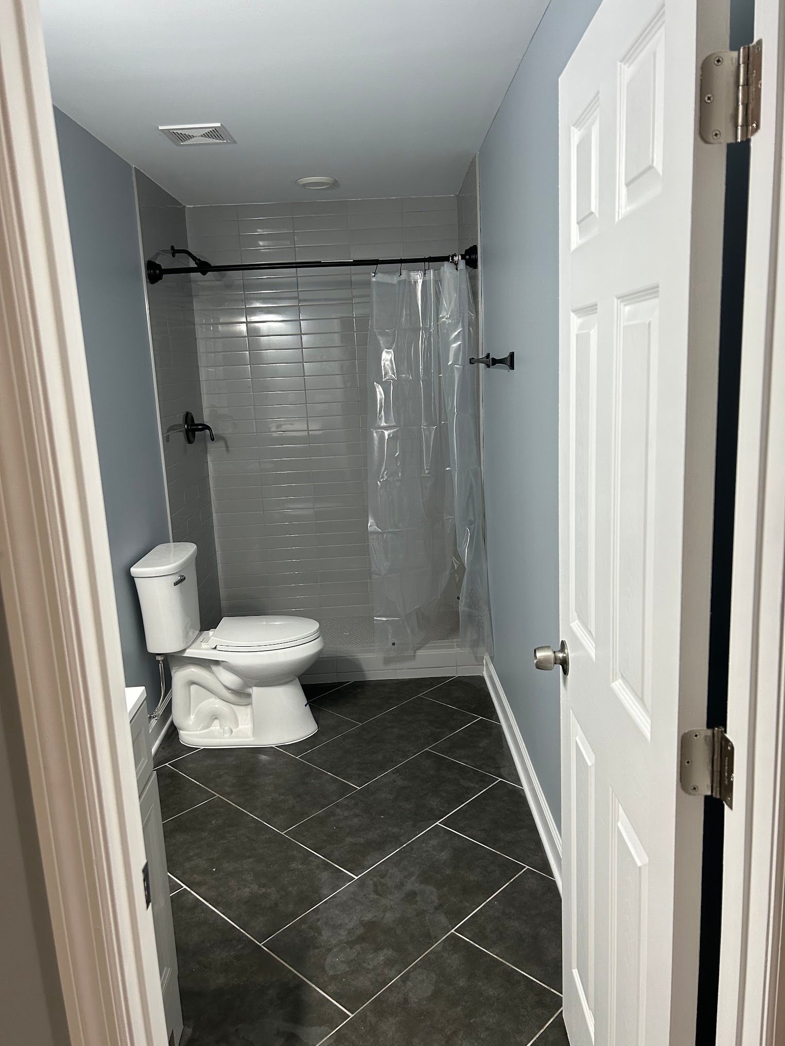 A bathroom with a toilet , shower and tile floor.